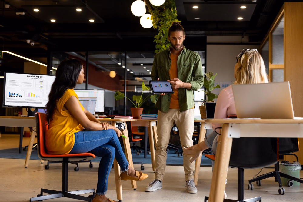 A team in an open-plan office with laptops and a tablet
